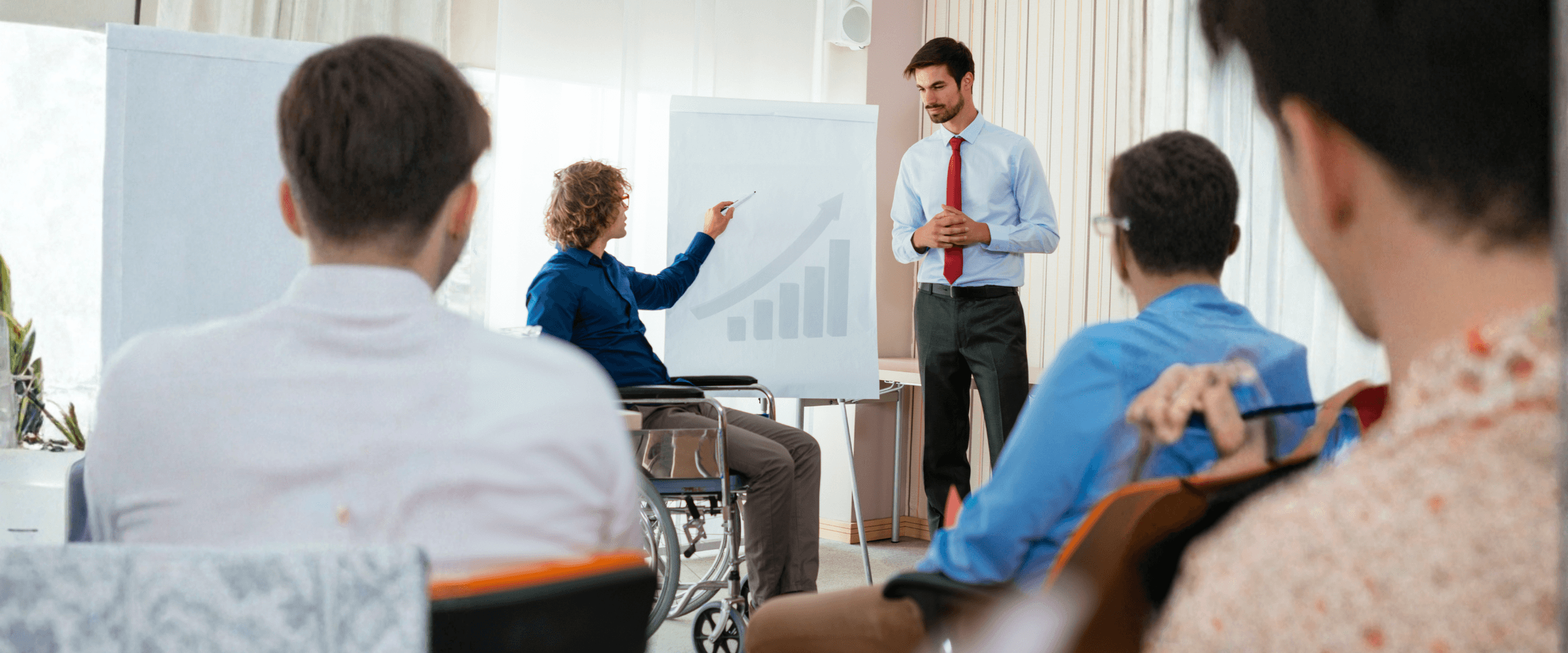 A woman in a wheelchair presenting in a meeting.