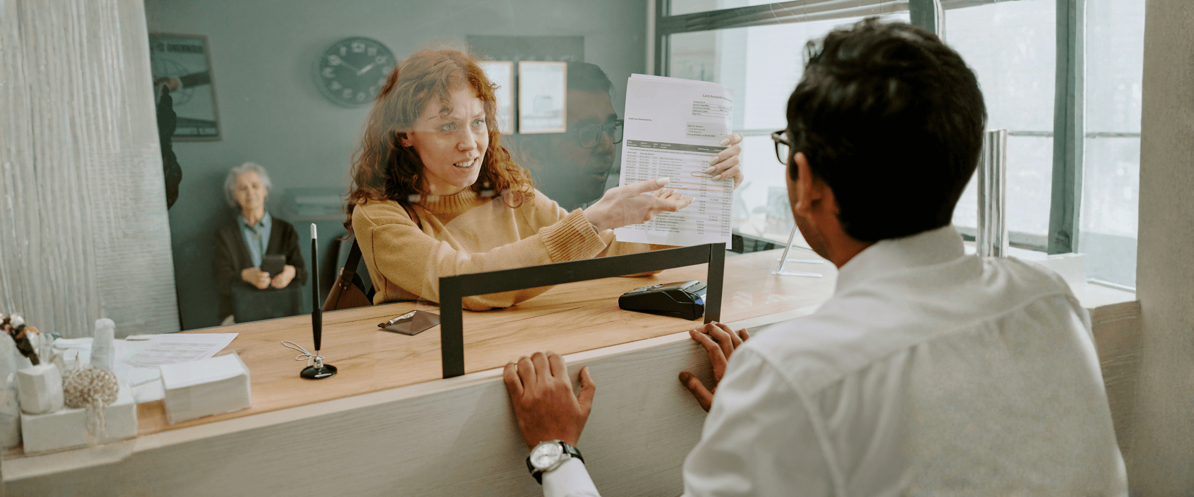 A woman holding up a paper in a bank.